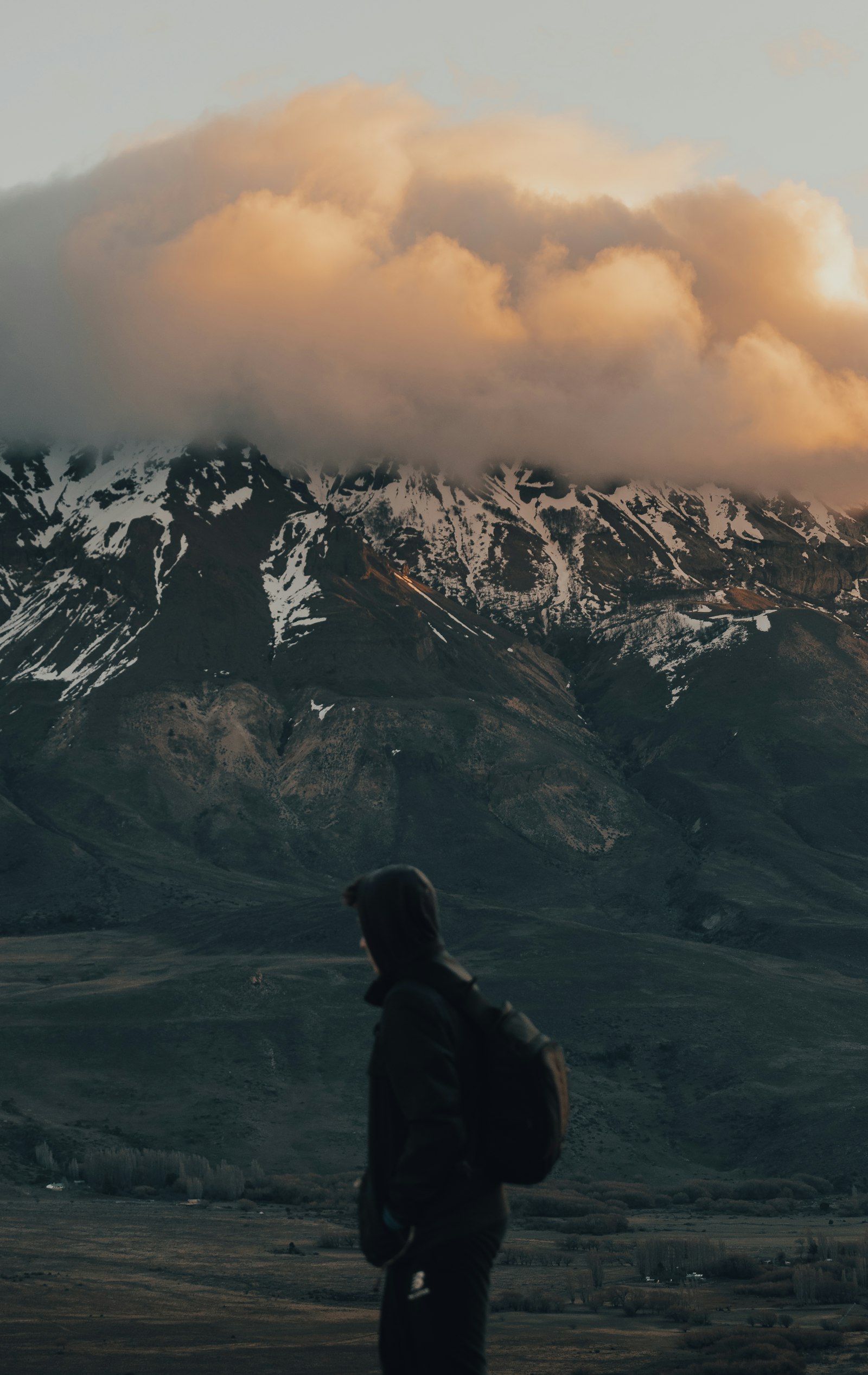 A traveler in winter outdoor gear looking out over snow-capped mountains